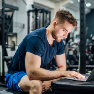 Man in gym researching on computer.
