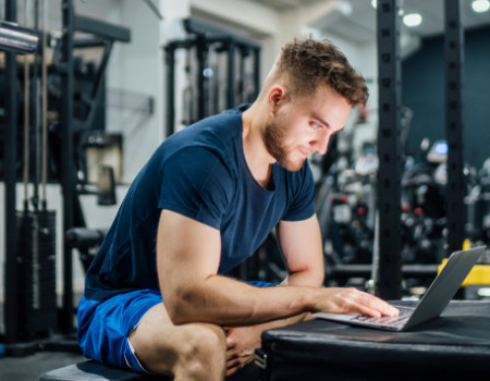 Man in gym researching on computer.